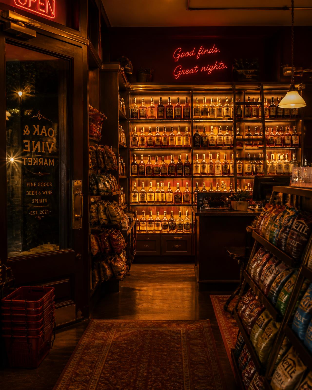 Backlit liquor shelves and tidy aisles inside Corner & Vine Market at night